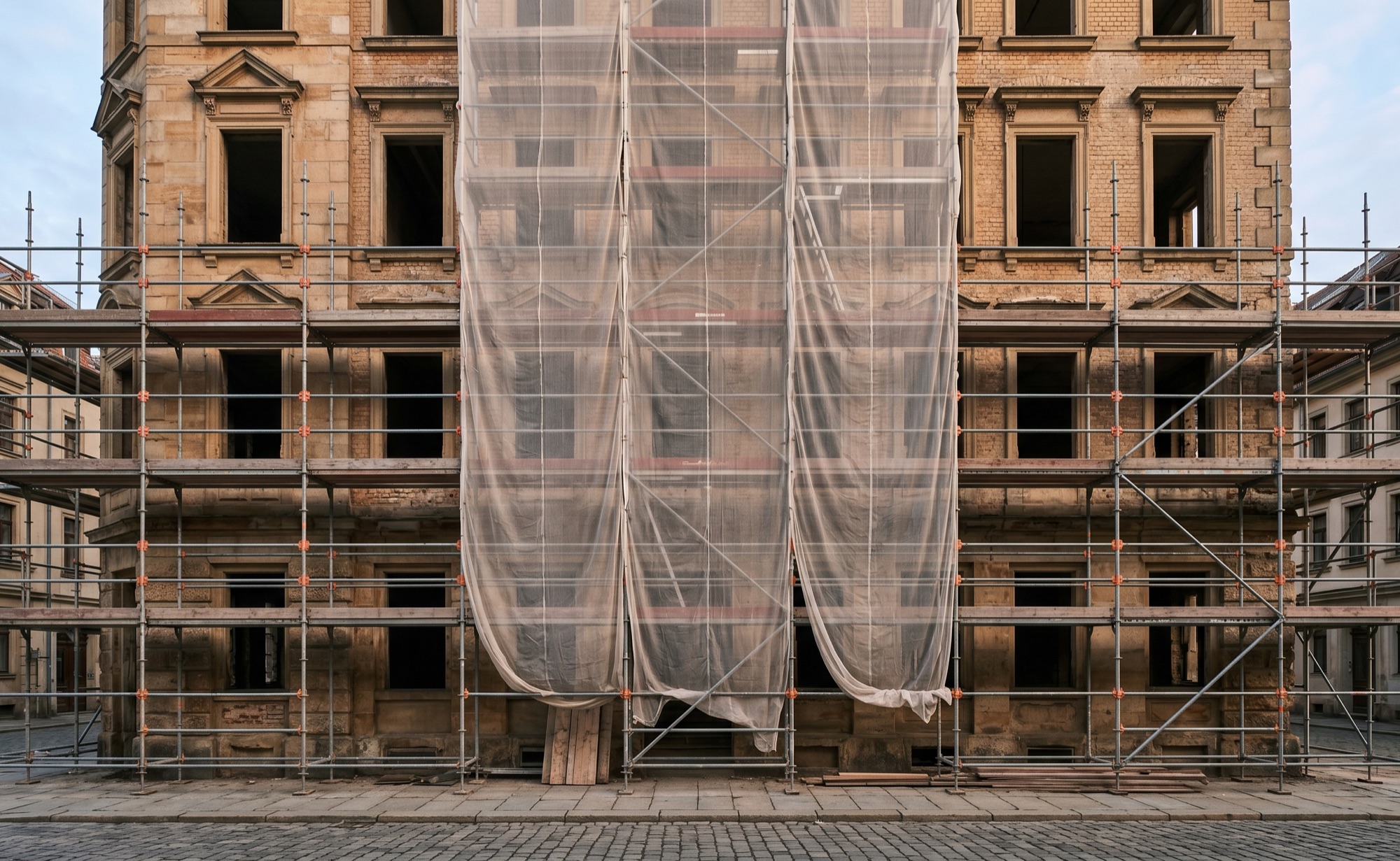 Husfasad under renovering med byggnadsställning och skyddsväv